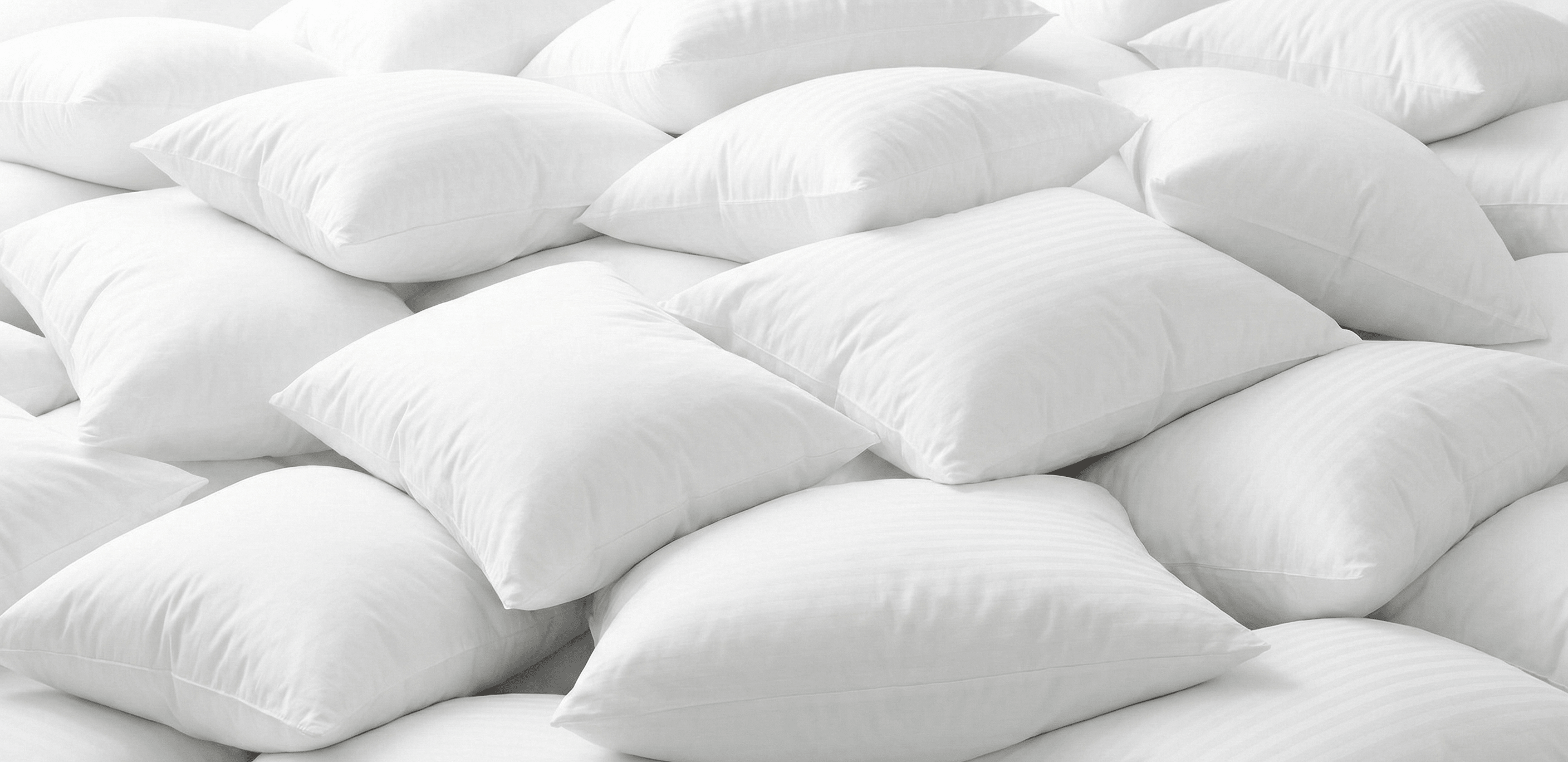 Massive cloud-like pile of pristine white hotel pillows with subtle stripe patterns, representing high-volume luxury inventory for hospitality businesses buying pillows in bulk.