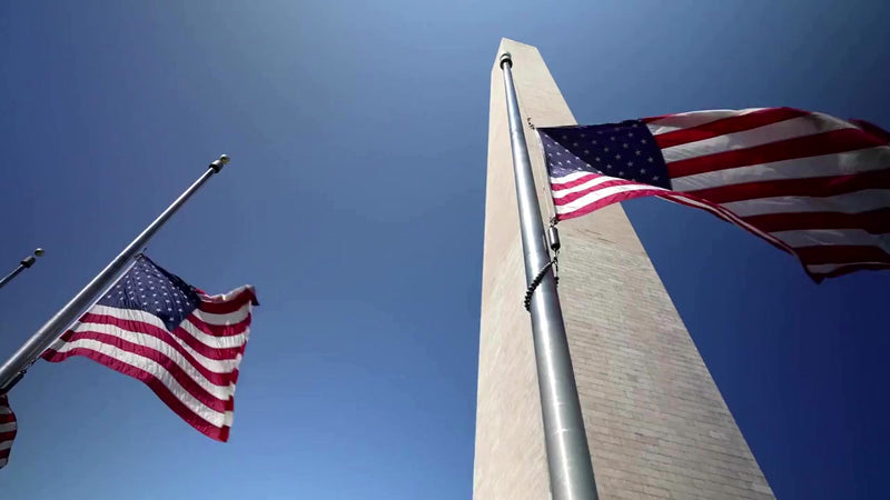 Panoramic video footage of the Washington Monument obelisk surrounded by waving US flags, symbolizing American heritage and a commitment to domestic supply chains for government contracting.